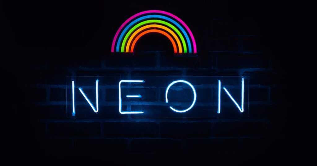 Colorful neon rainbow and text sign against a dark backdrop.