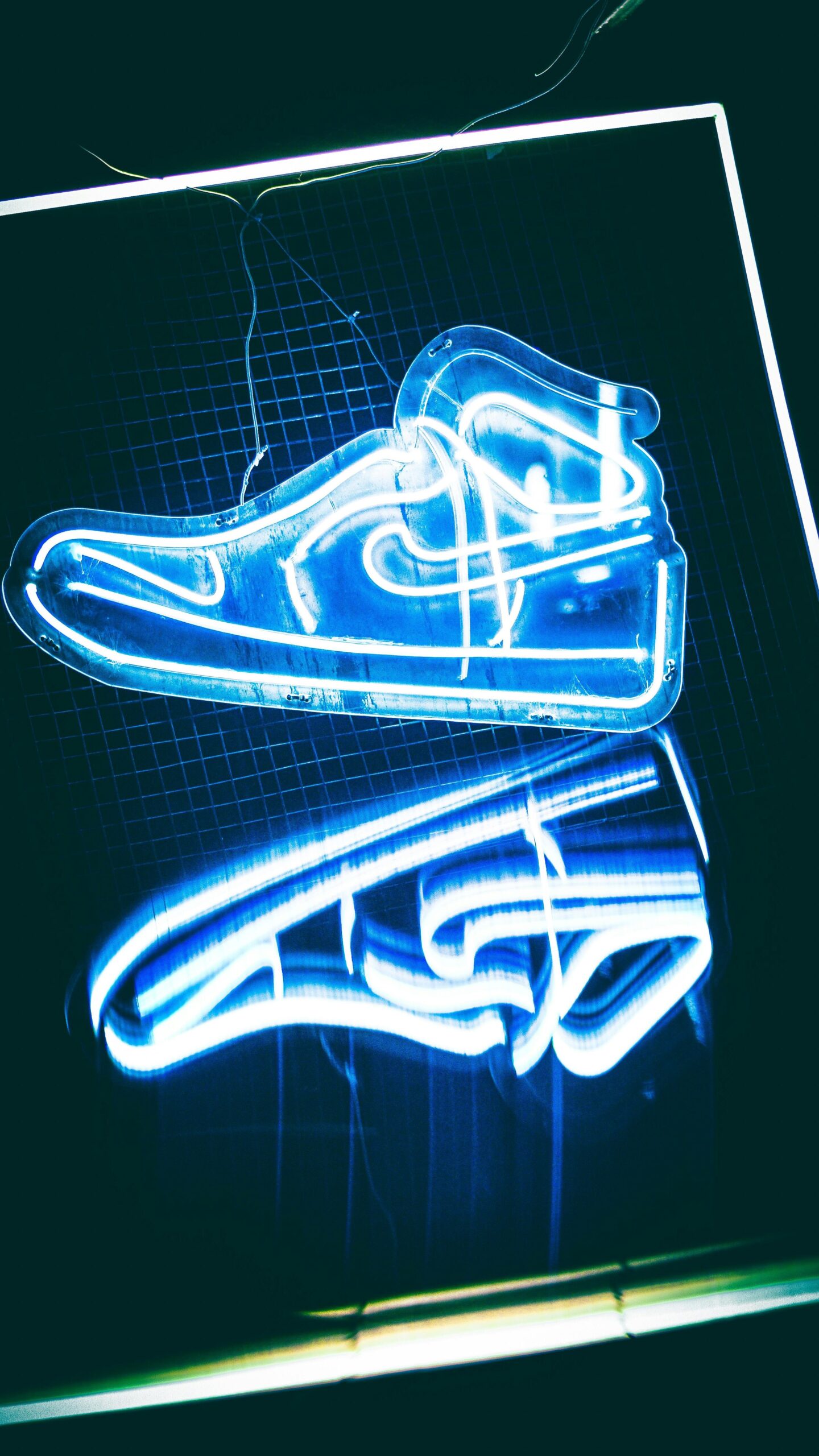 Vibrant neon sign shaped as a shoe, glowing in blue, adds modern artistic flair.