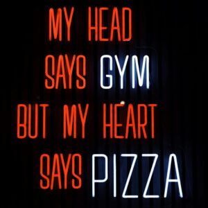 Colorful neon sign humorously declares 'My head says gym but my heart says pizza' in Jönköping, Sweden.