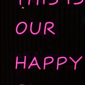 Vibrant pink neon sign reading 'This is our happy place' in Lisbon, Portugal.